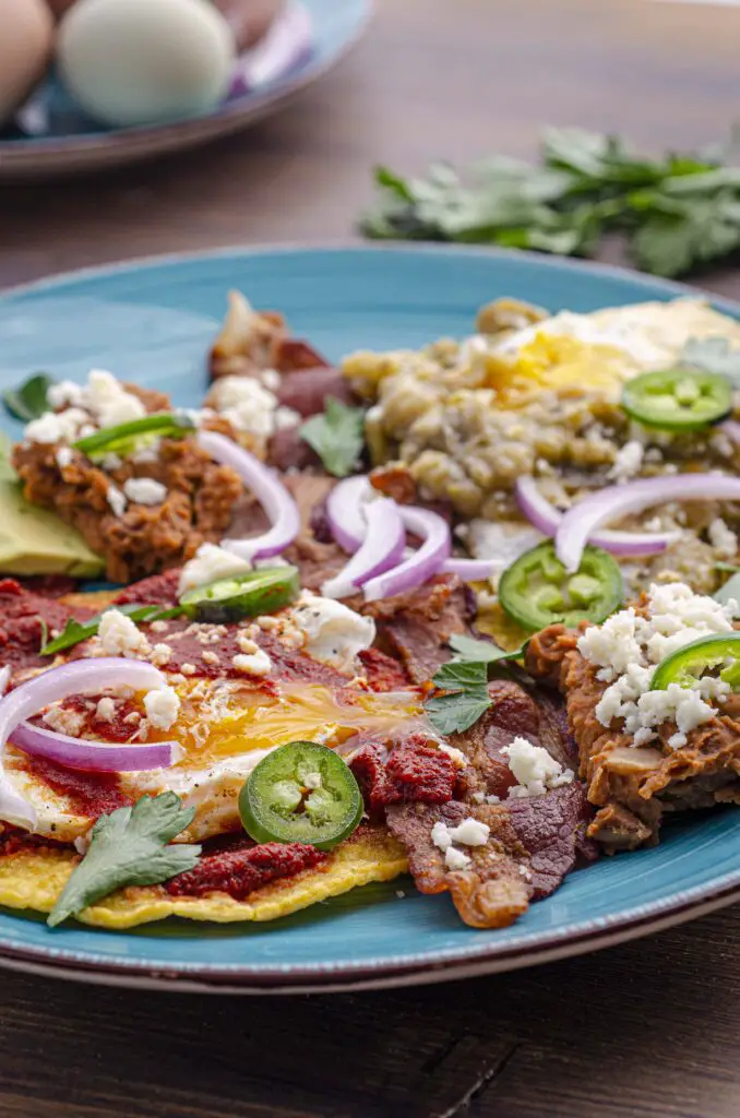 A closeup of a plate full of huevos divorciados garnished with red onion and jalapeno slices.