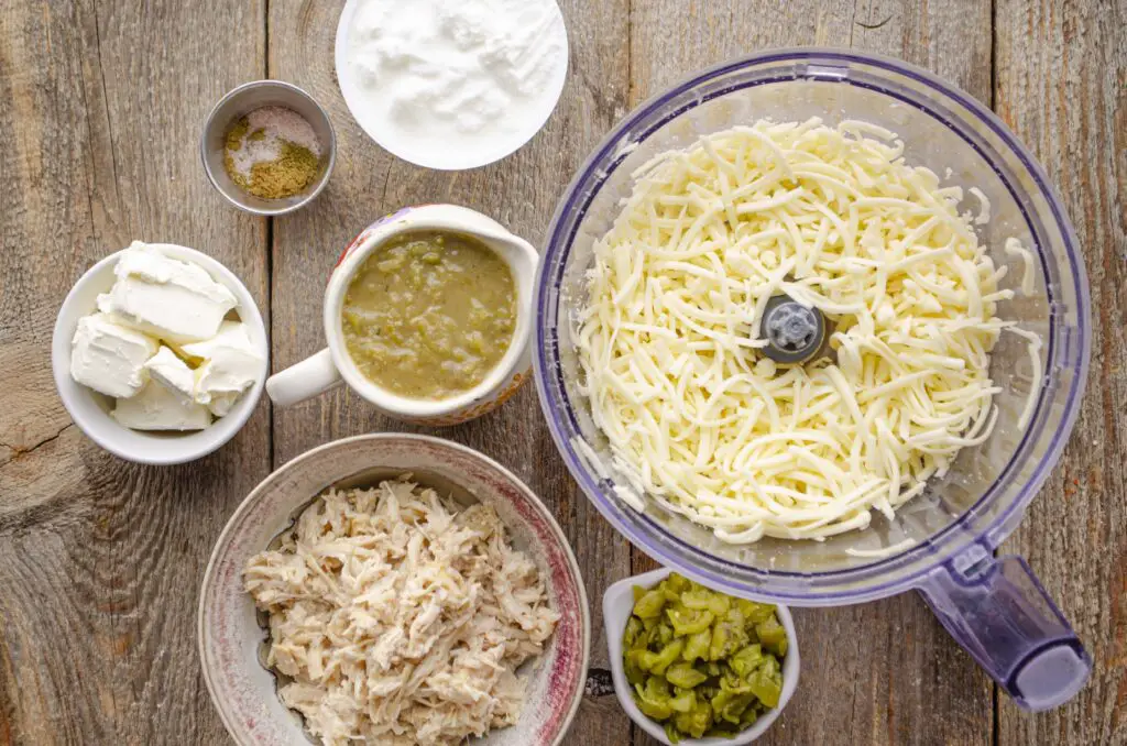 Looking down on all the ingredients, such as shredded cheese, green chile, cream cheese, and shredded chicken, measured and prepared to make Skinny Hatch Green chile Chicken dip.
