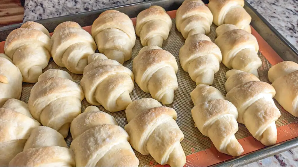 A rimmed baking sheet full of golden freshly baked potato rolls made with instant potatoes.