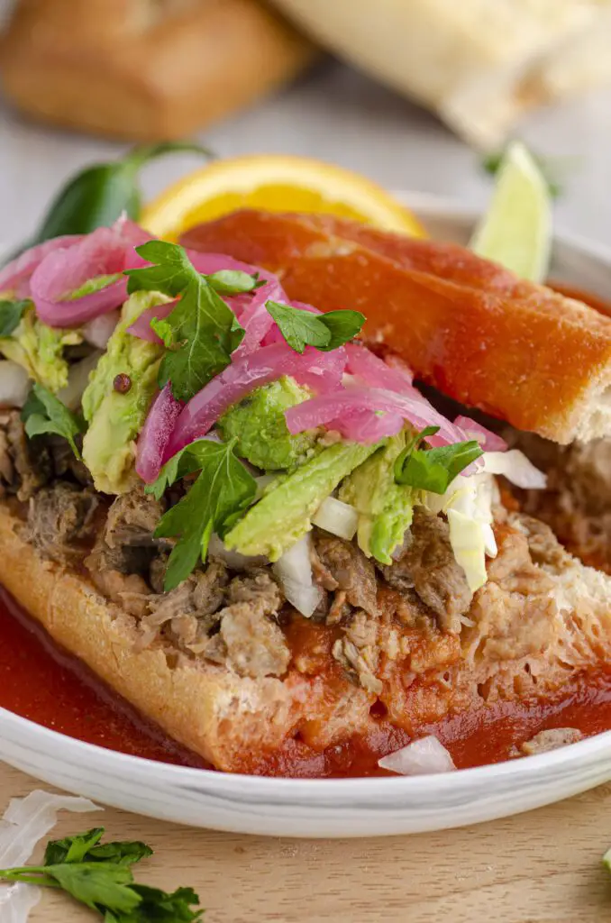 A very close picture showing the toppings and texture of a torta ahogada sandwich.