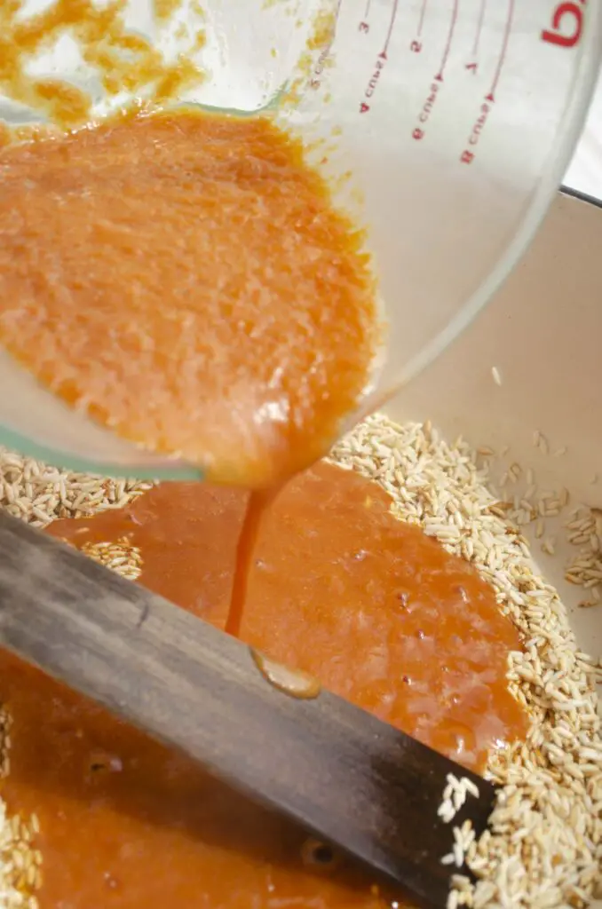 Tomato puree is poured into a Dutch oven with toasted rice to make Mexican rice.