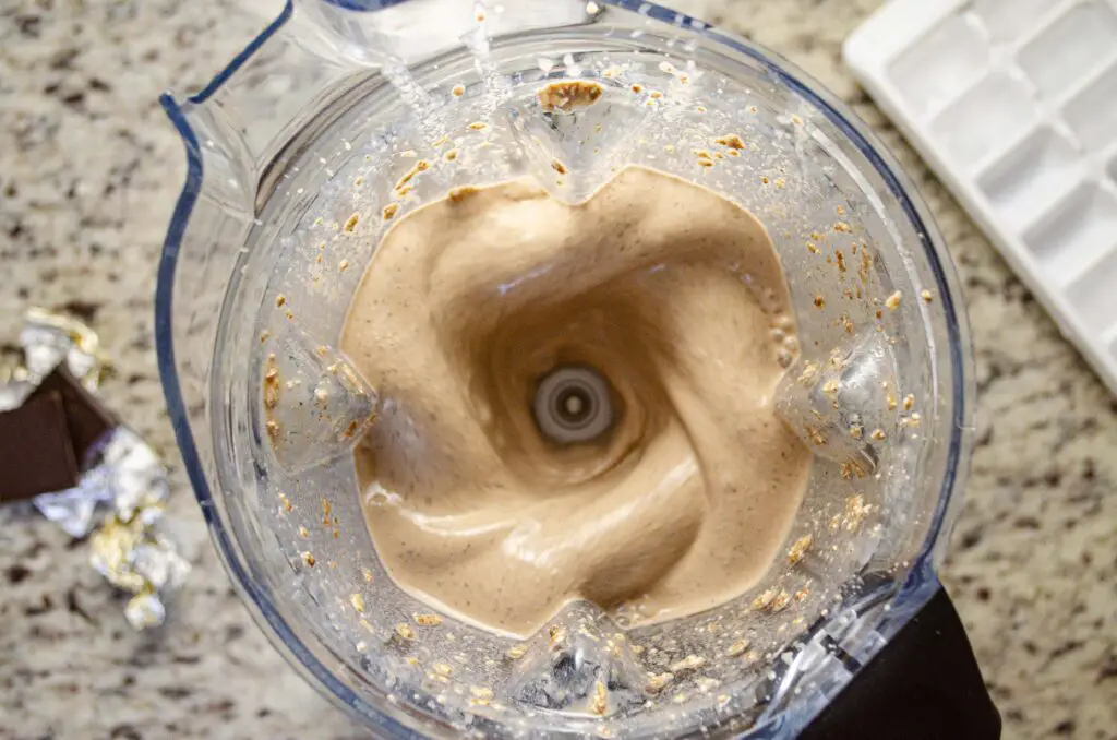 Looking down into a blender running and making Chocolate Peanut Butter Banana Naked Oats smoothie.