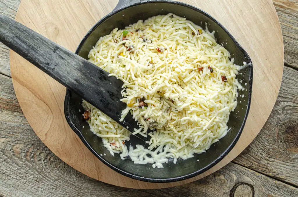  Looking down into a cast-iron skillet full of white shredded cheese.